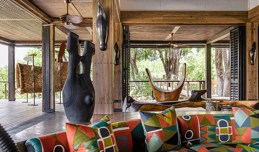 Xigera Safari Lodge’s boma lit for an evening under the stars, with a central firepit and beautifully set dining tables.